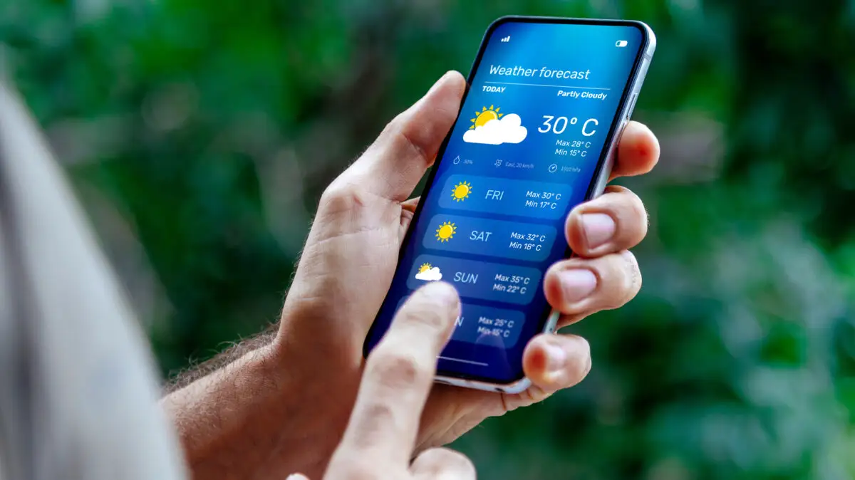 Persoană care consultă prognoza meteo pe mai multe zile pe ecranul unui telefon mobil